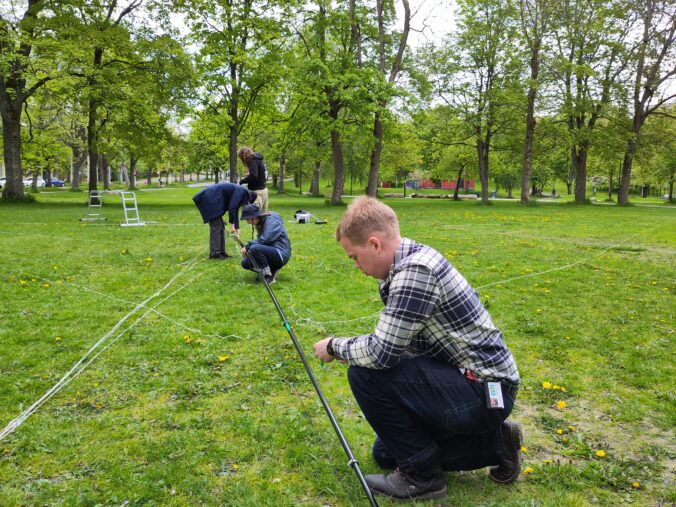 The mast still on the ground while everyone is working on it.